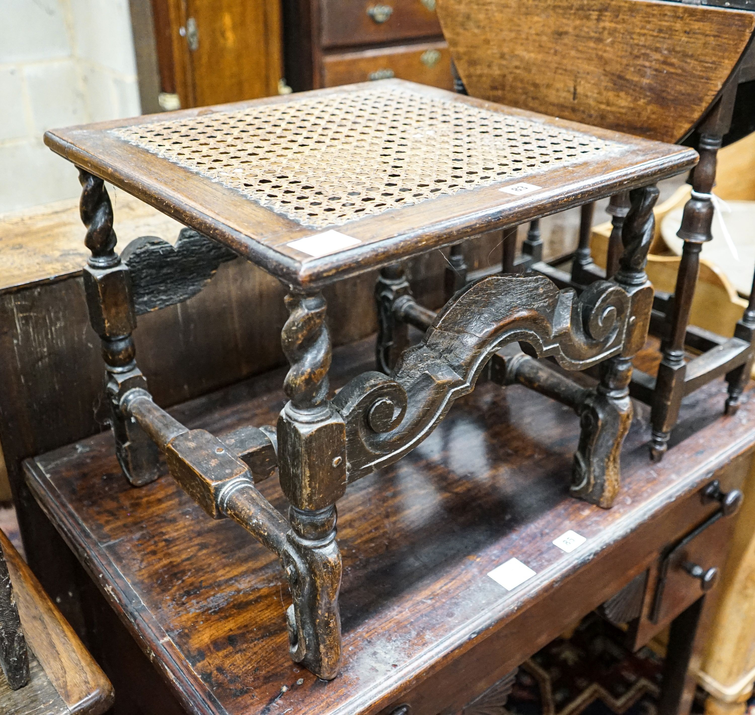 A 17th century style carved oak stool, with caned seat and H stretcher, width 47cm, depth 46cm, height 42cm